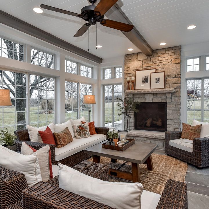 a living room filled with lots of furniture next to a fire place under a ceiling fan