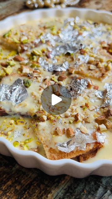 a white dish filled with food on top of a wooden table next to silver foil