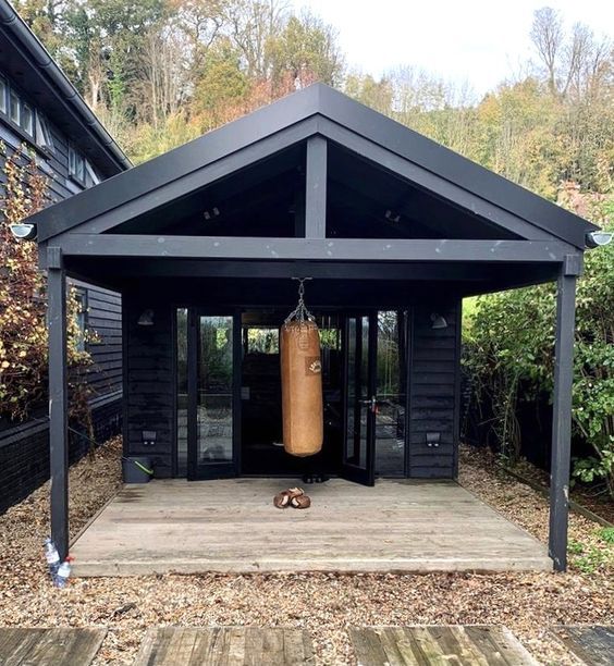 a wooden deck with a boxing bag hanging from it's side in front of a black building