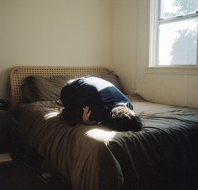 a person laying on top of a bed in a bedroom next to a large window