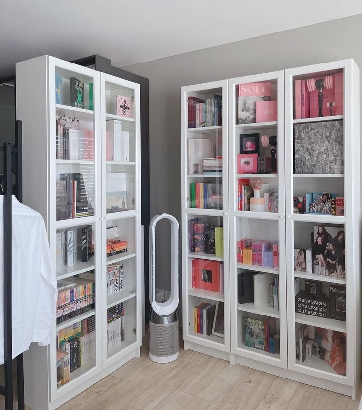 a white bookcase filled with lots of books on top of a hard wood floor