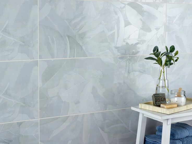 a bathroom with blue towels and a plant in a vase on the table next to it