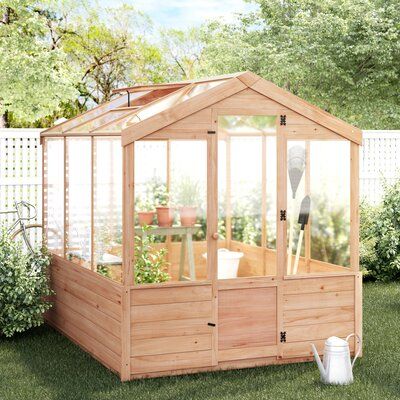 a small wooden greenhouse in the grass