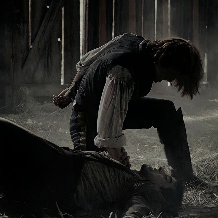 a woman kneeling down next to a dead animal on the ground in a hay field