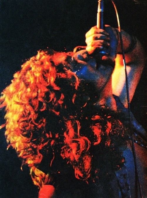 a woman with red hair holding a microphone in front of her face while performing on stage