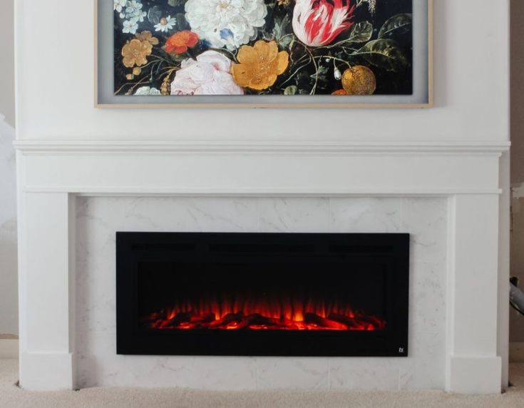 a white fireplace with a painting on the wall above it and a fire place in front of it