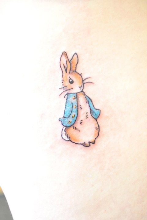 a small rabbit tattoo on the back of a woman's stomach