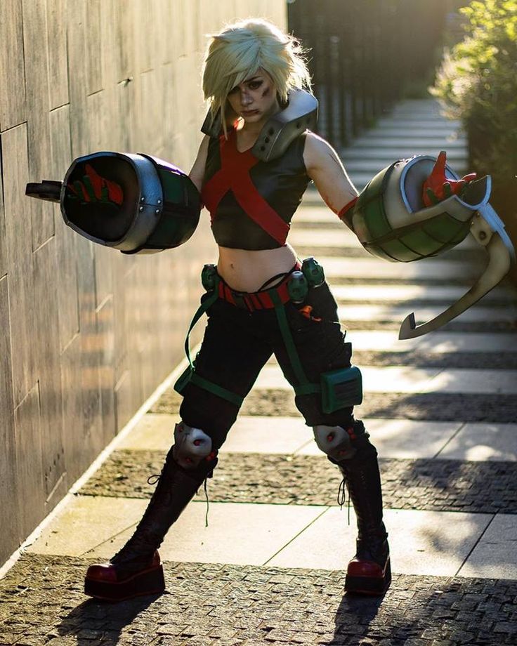 a woman dressed in cosplay clothing and holding two large metal objects while standing on the sidewalk