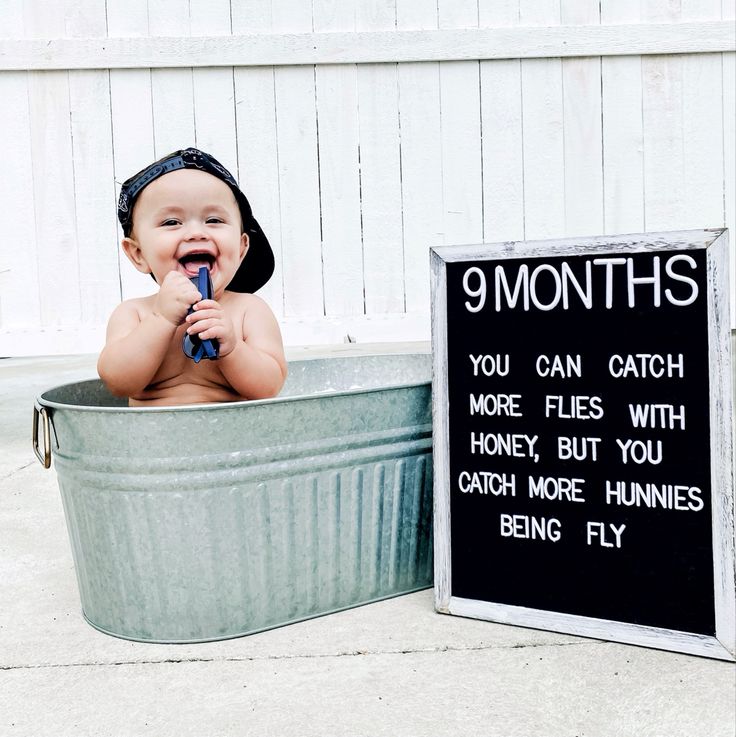 a baby sitting in a tub with a sign next to it