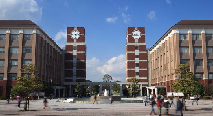 two large brick buildings with clocks on them in the middle of a courtyard surrounded by people