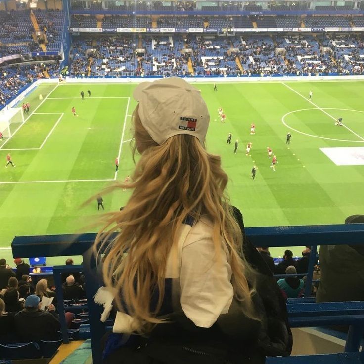 a woman sitting in the stands watching a soccer game