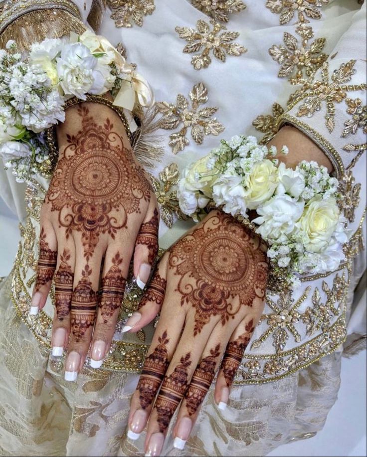 two hands with henna designs on them and flowers in the middle of each hand