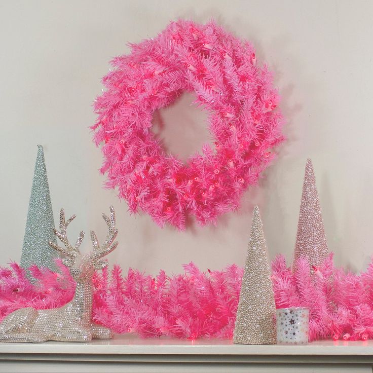 pink and silver christmas decorations on top of a mantel with a wreath above it