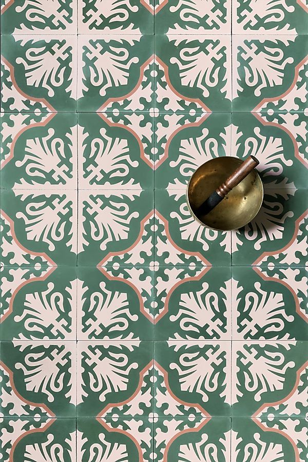 a green and white tiled wall with a brass bell