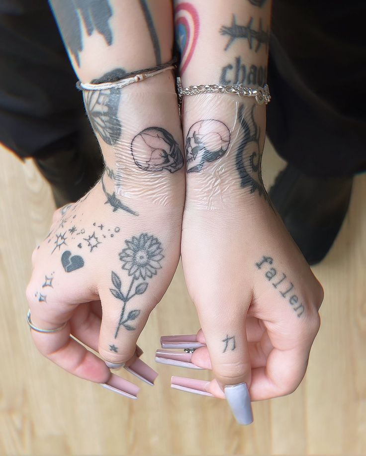 two people with tattoos on their arms holding onto each other's hands and fingers