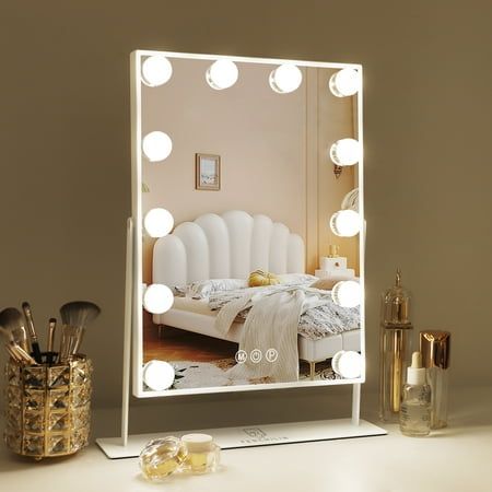 a vanity mirror with lights on top of it in front of a desk and other items