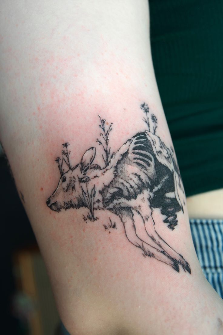 a woman with a tattoo on her arm that has a deer and flowers on it