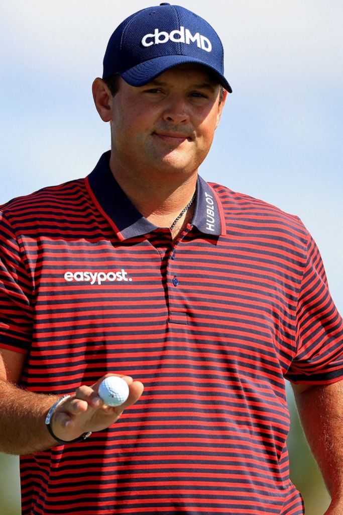 a man wearing a red and black striped shirt holds a golf ball in his hand