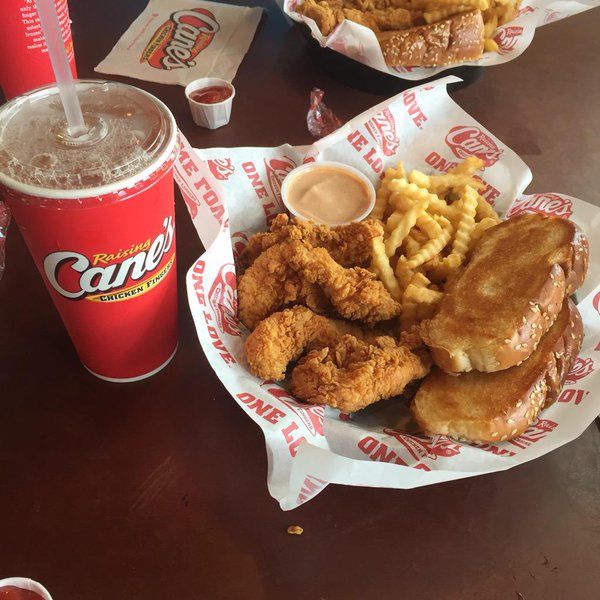 chicken, waffles and french fries are on the table next to two cups of soda