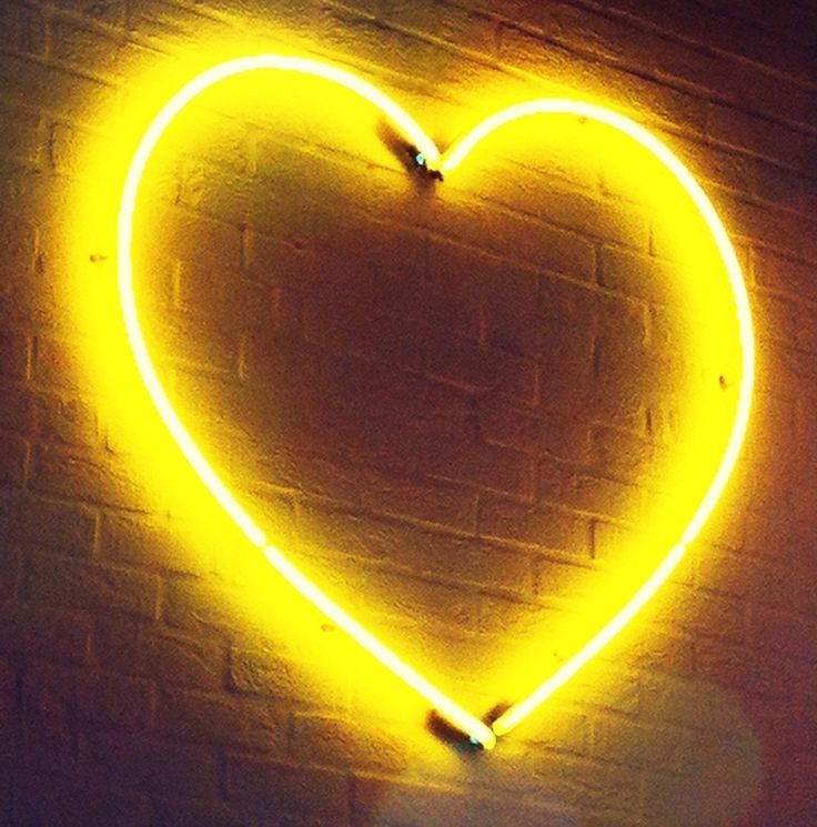 a heart shaped neon sign on a brick wall