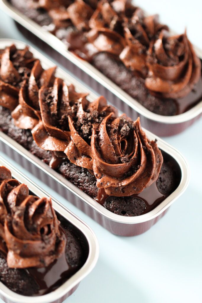 three trays filled with chocolate cupcakes covered in frosting