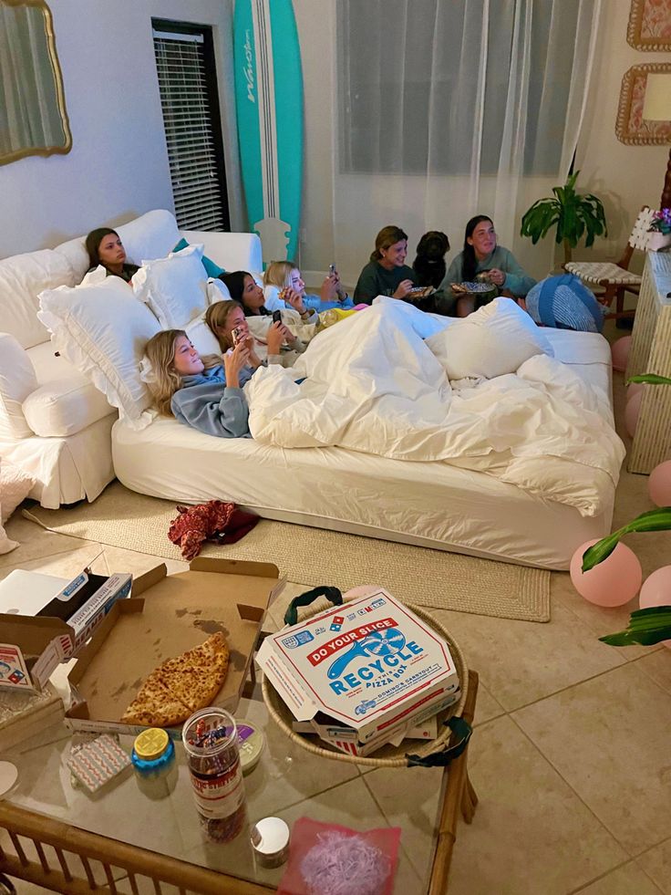 a group of people laying on top of a bed in a living room next to each other