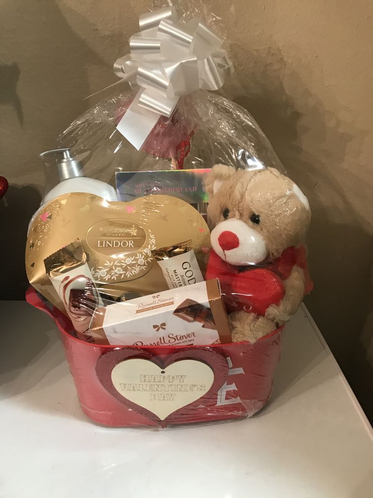 a teddy bear sitting in a red basket filled with personal care products and soaps