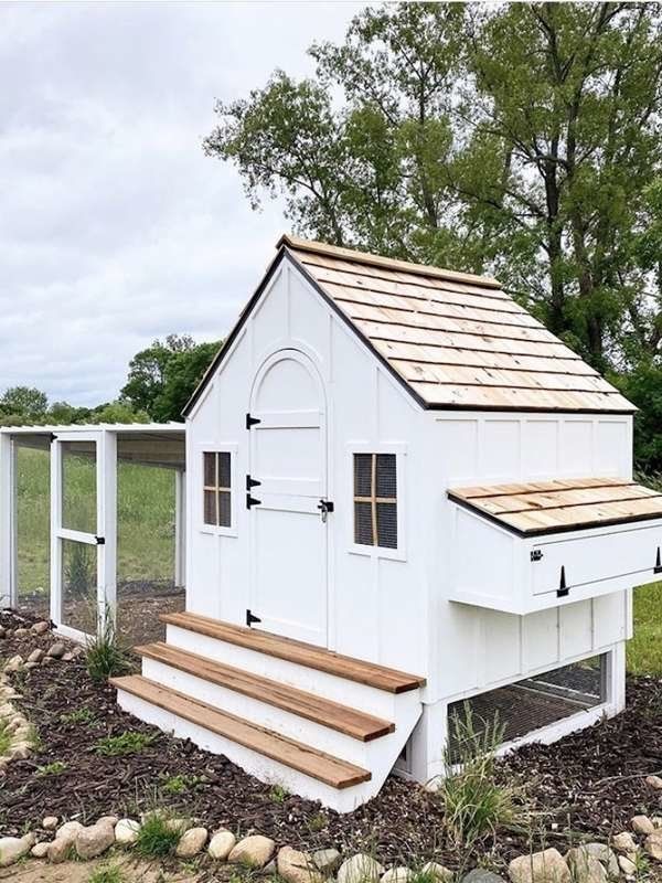 a white chicken coop with steps leading up to the door and windows on each side