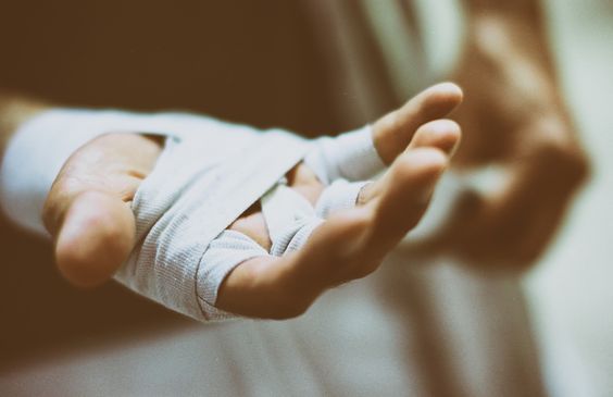 a person with bandaged hands holding something in their palm and wearing an arm cast