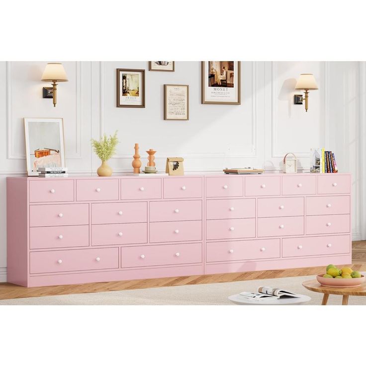 a pink dresser in a white room with pictures on the wall