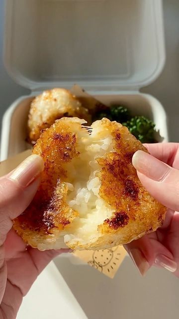 a person holding up a piece of food in front of a container with broccoli