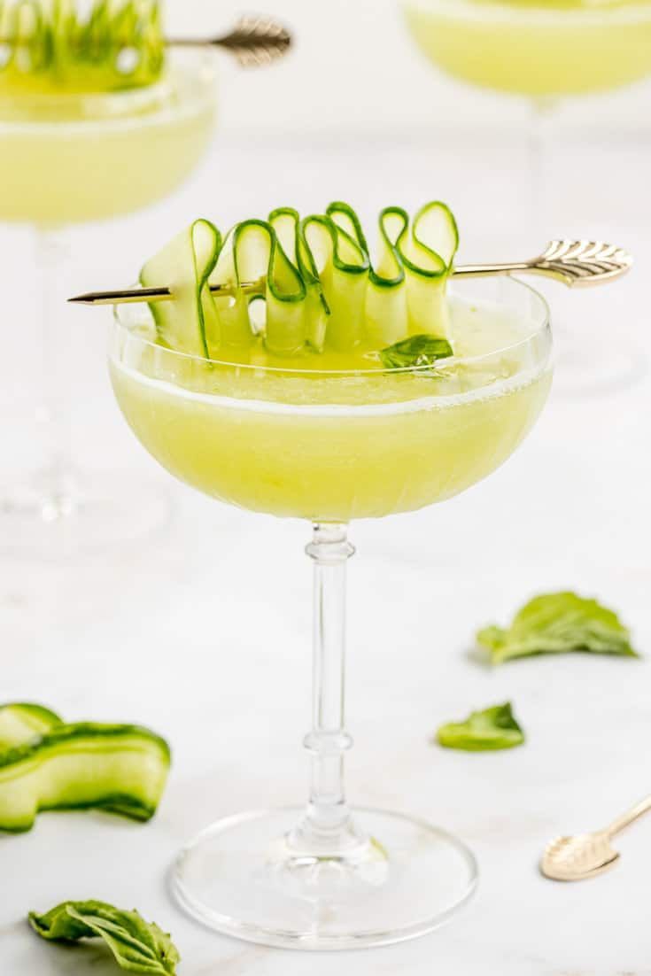 two glasses filled with drinks and garnished with cucumbers