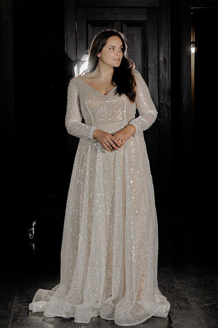 a woman in a white dress standing on a tile floor with her hands behind her back