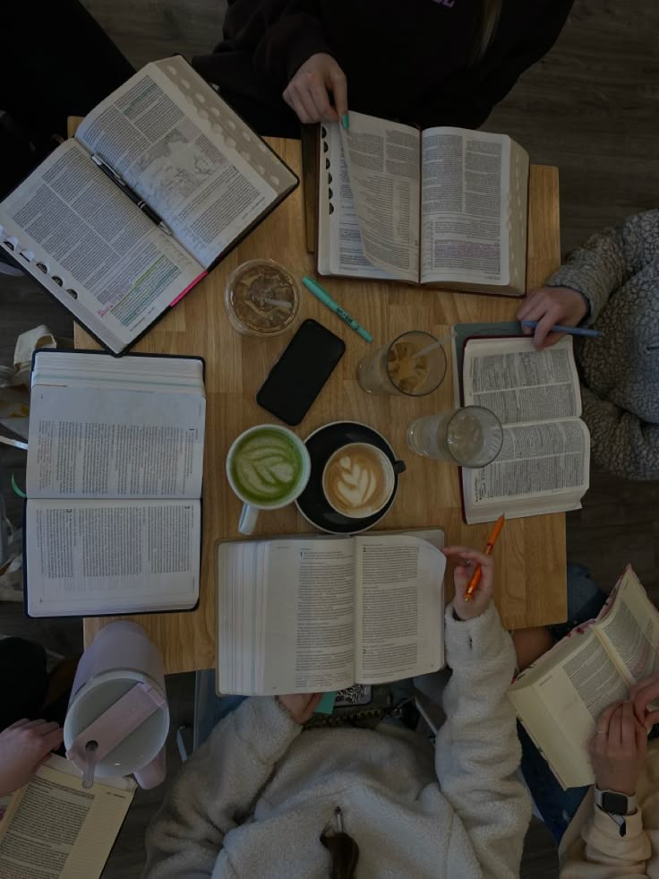 several people sitting at a table with open books