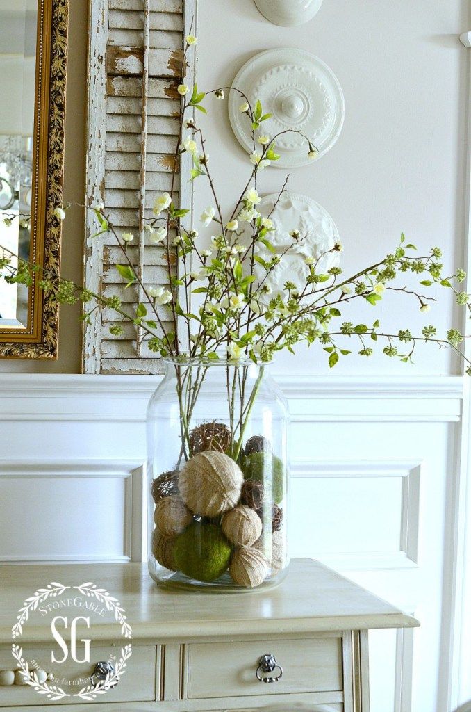 a vase filled with flowers sitting on top of a white table next to a mirror