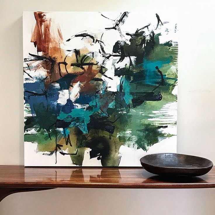 a painting on a wall next to a black bowl and wooden table in front of it