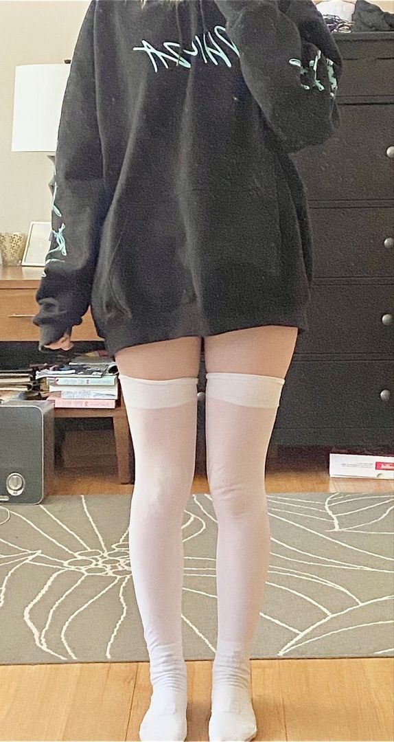 a woman in white stockings and thigh high socks is looking at her reflection in the mirror