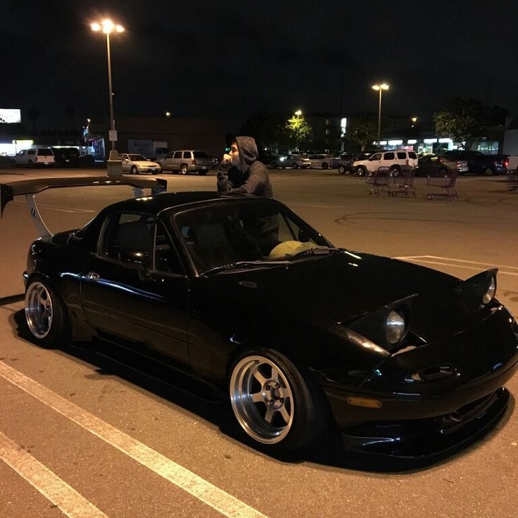 a black sports car parked in a parking lot with the hood up and lights on