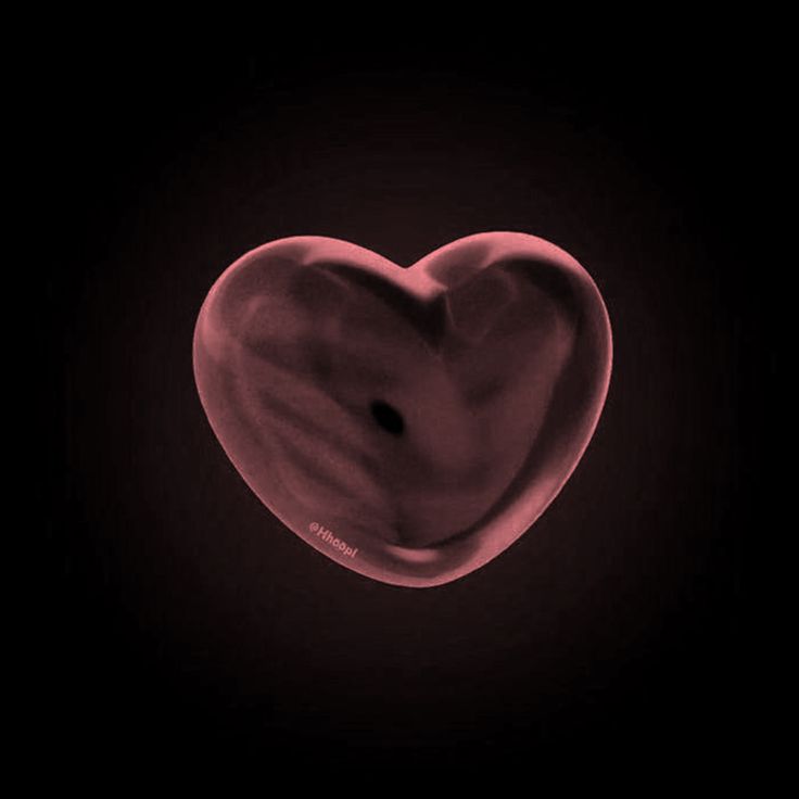 a heart shaped object in the dark with a black background and some red light coming from it