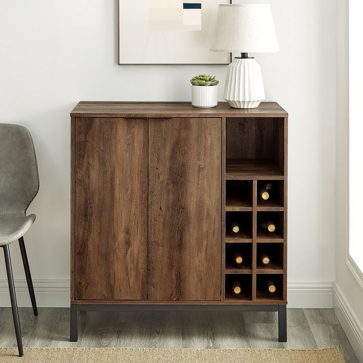 a wooden cabinet with wine bottles in it next to a gray chair and white wall