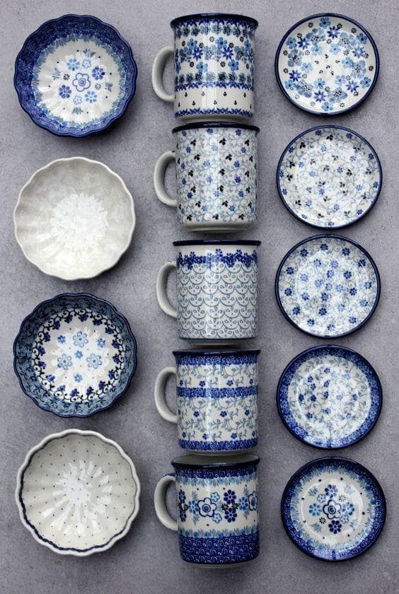 blue and white dishes are arranged on a gray surface with matching cups and saucers