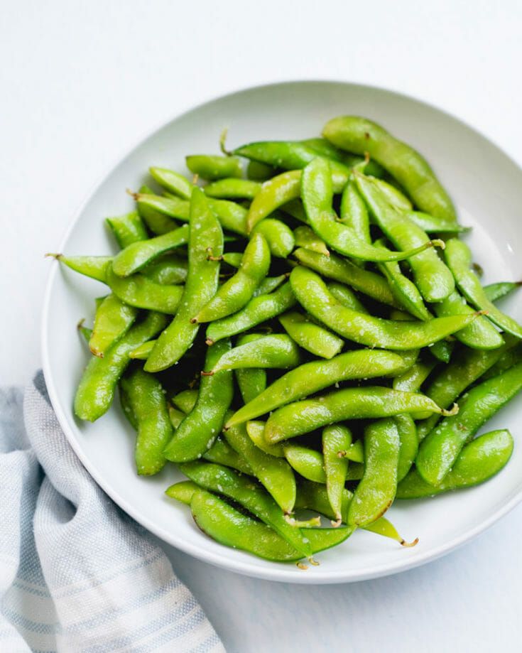 a white bowl filled with green beans on top of a table