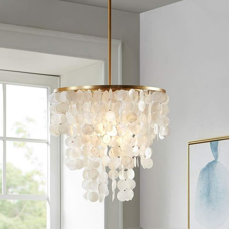 a chandelier hanging from the ceiling in a room with white walls and windows