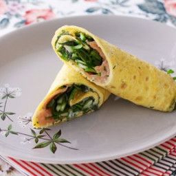 a white plate topped with an omelet filled with meat and veggies