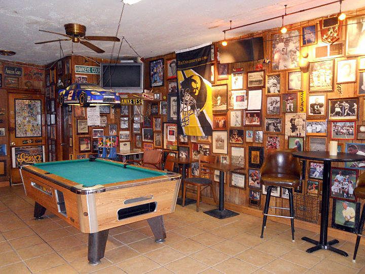 a pool table in a room with many pictures on the wall