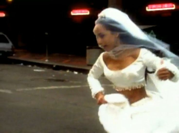 a woman in a white wedding dress is walking down the street