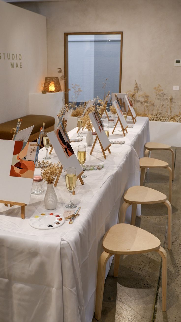 a long table with paintings and wine glasses on it