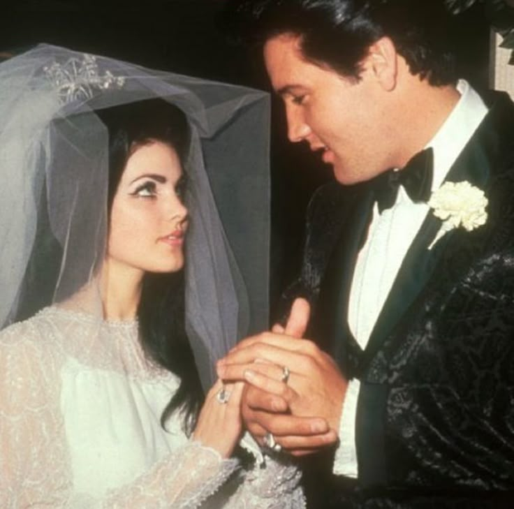 a man and woman standing next to each other in front of a wedding veil on their head