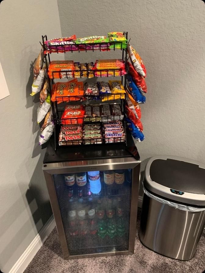 an ice chest with snacks and drinks on it next to a trash can in the corner