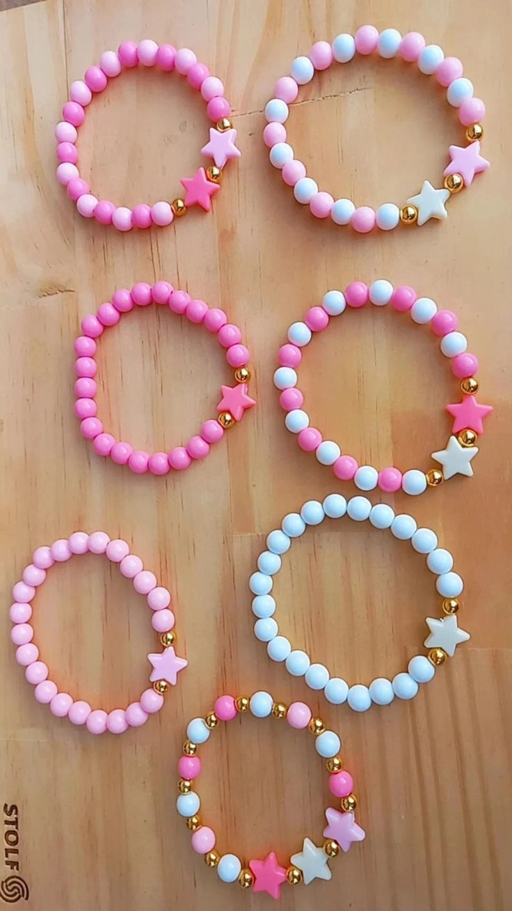 six bracelets with pink, white and blue beads on top of a wooden table